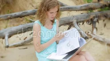 一个忙碌的年轻女子正在用一台手提电脑，手里拿着商业文件，拿起一个电话，坐着打电话